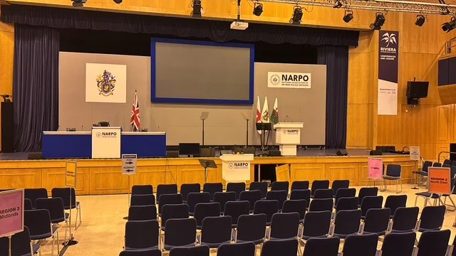 The conference hall set out for NARPO Conference 2026, with the NARPO crest and lecterns on stage and regional seating signs